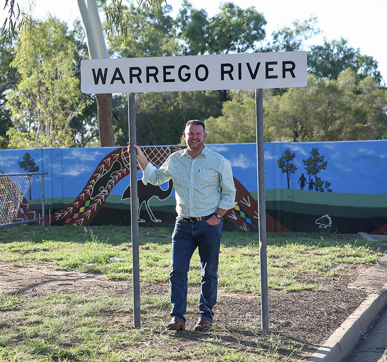 Shane Charles standing in front of Warrego River sign.